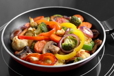 Photo of Frying pan with mix of vegetables and mushrooms on cooktop, closeup