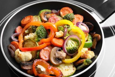 Photo of Frying pan with mix of vegetables and mushrooms on cooktop, closeup