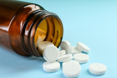 Photo of Bottle of antibiotic pills on light blue background, closeup