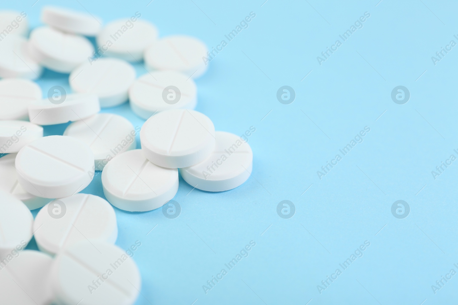 Photo of Many antibiotic pills on light blue background, closeup. Space for text