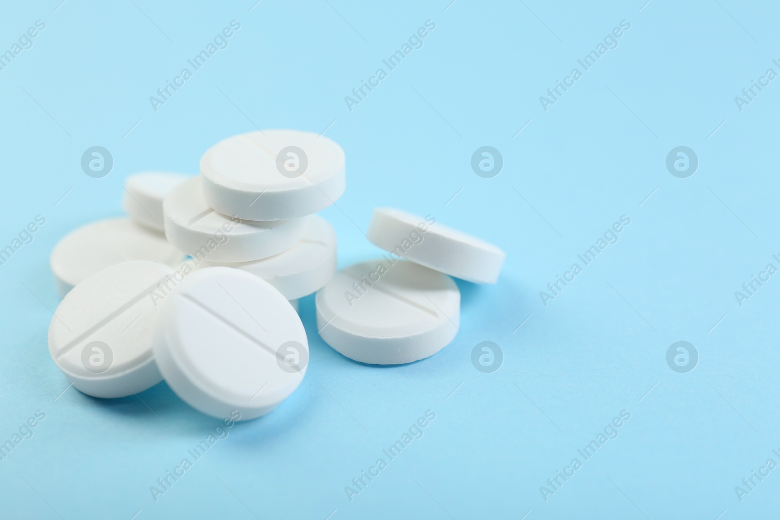 Photo of Many antibiotic pills on light blue background, closeup. Space for text