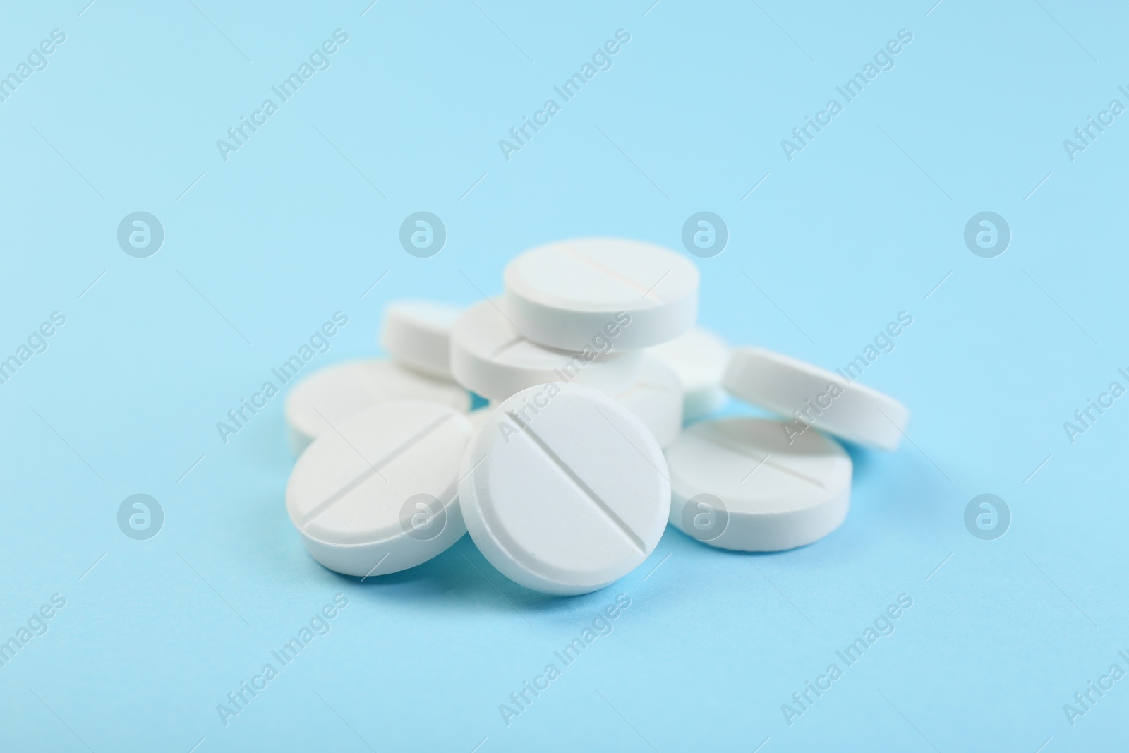 Photo of Many antibiotic pills on light blue background, closeup