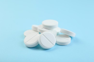 Photo of Many antibiotic pills on light blue background, closeup