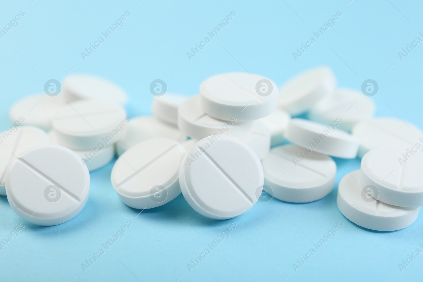 Photo of Many antibiotic pills on light blue background, closeup