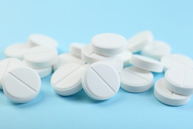 Photo of Many antibiotic pills on light blue background, closeup