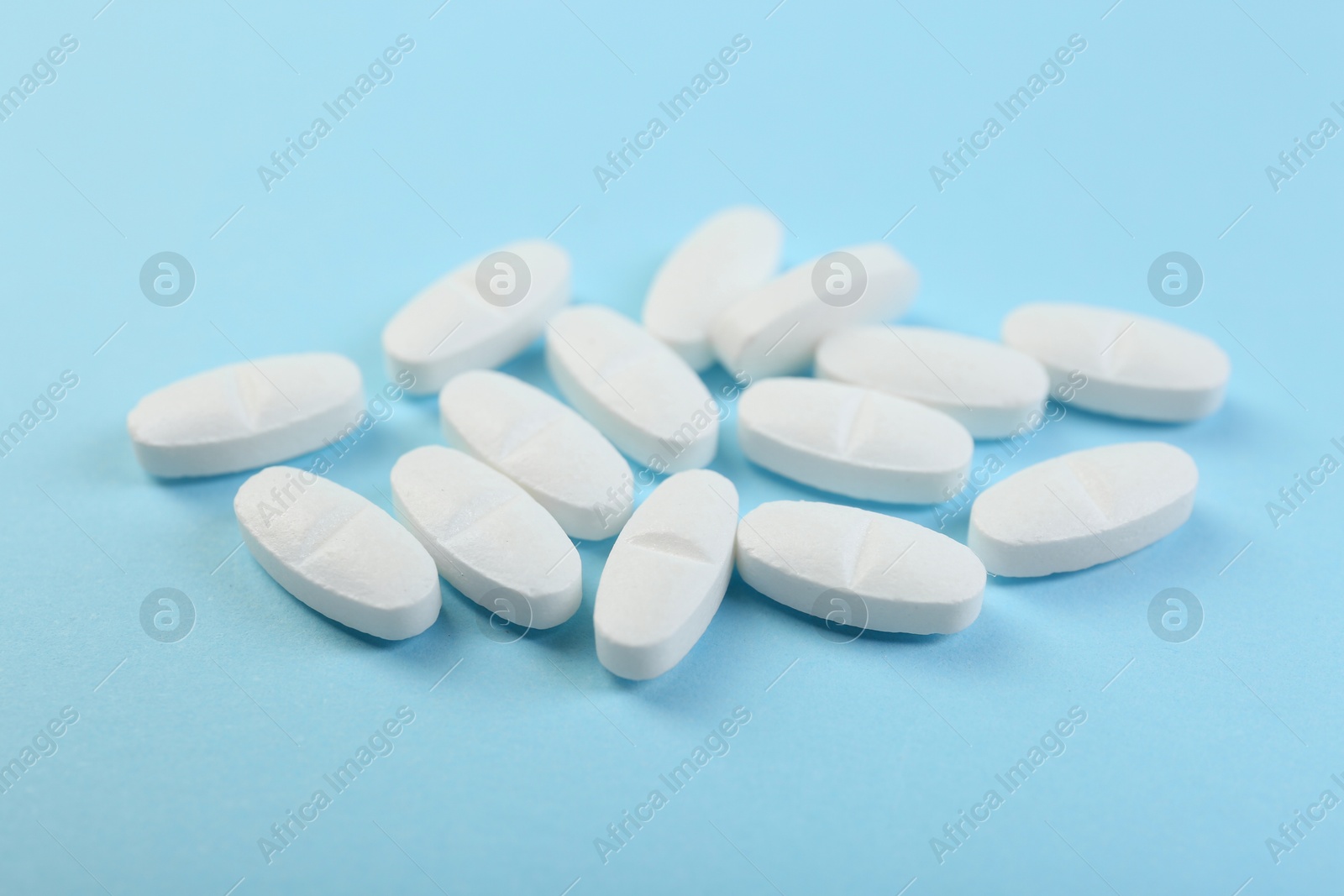 Photo of Many antibiotic pills on light blue background, closeup