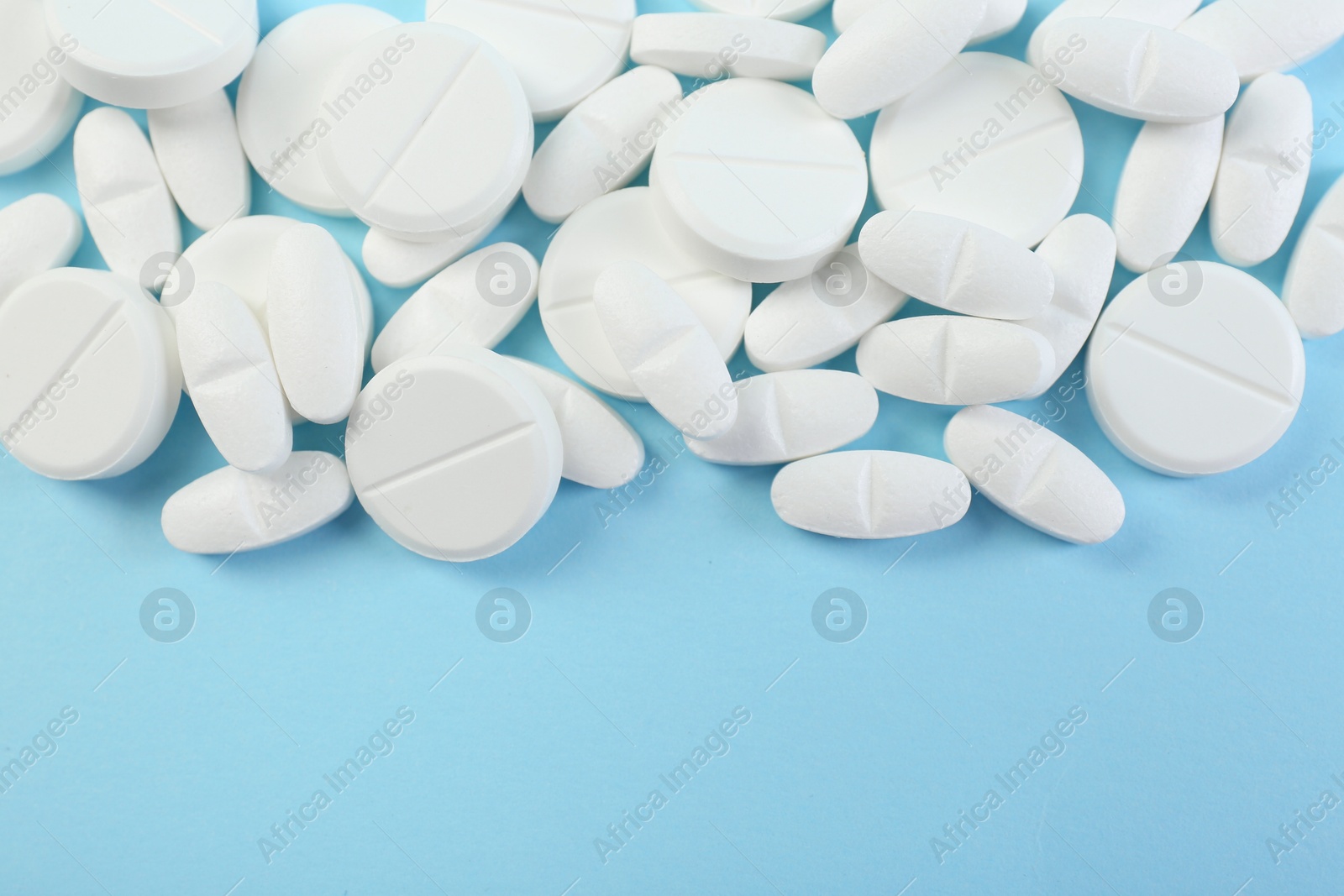 Photo of Many antibiotic pills on light blue background, top view. Space for text