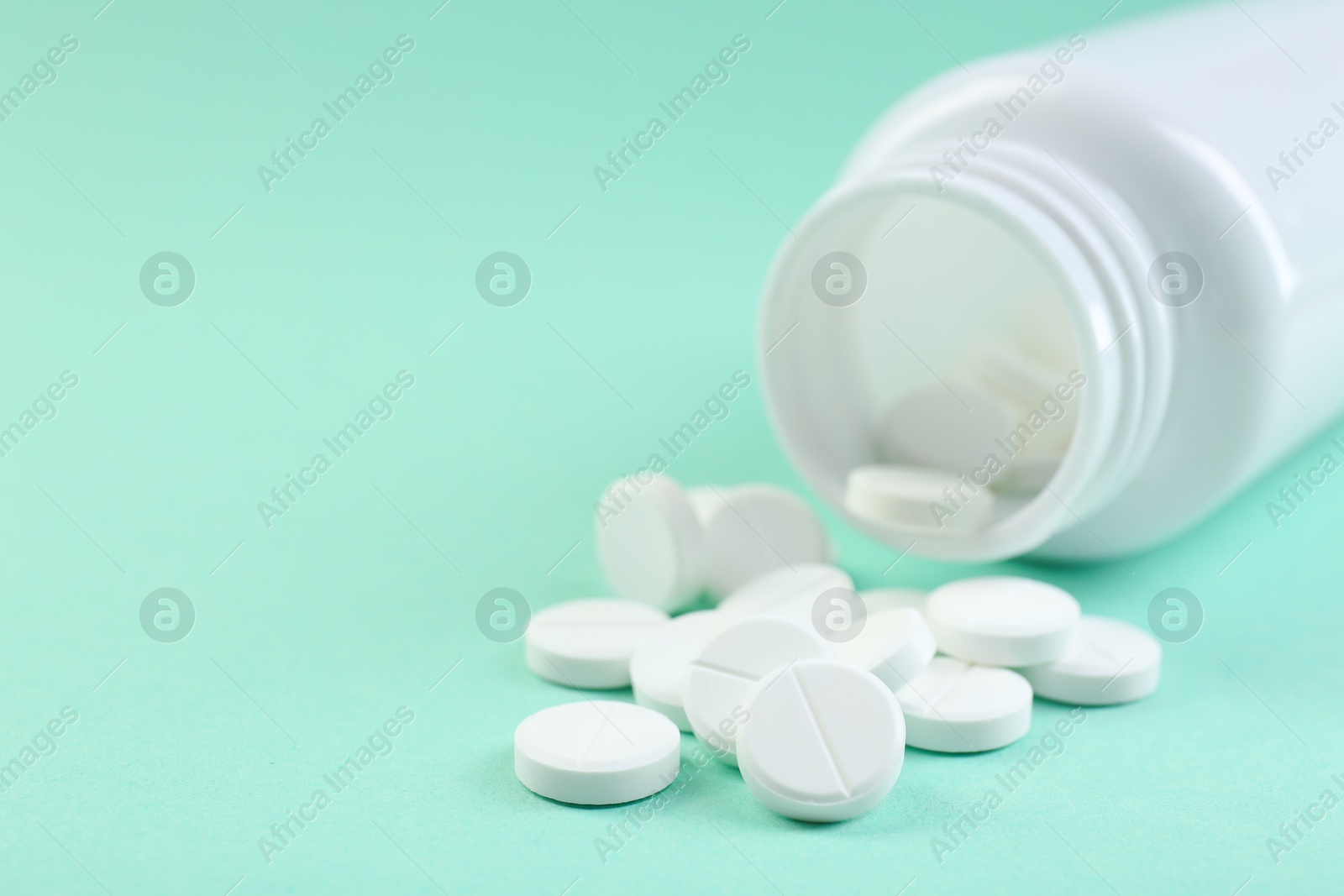 Photo of Bottle of antibiotic pills on turquoise background, closeup. Space for text