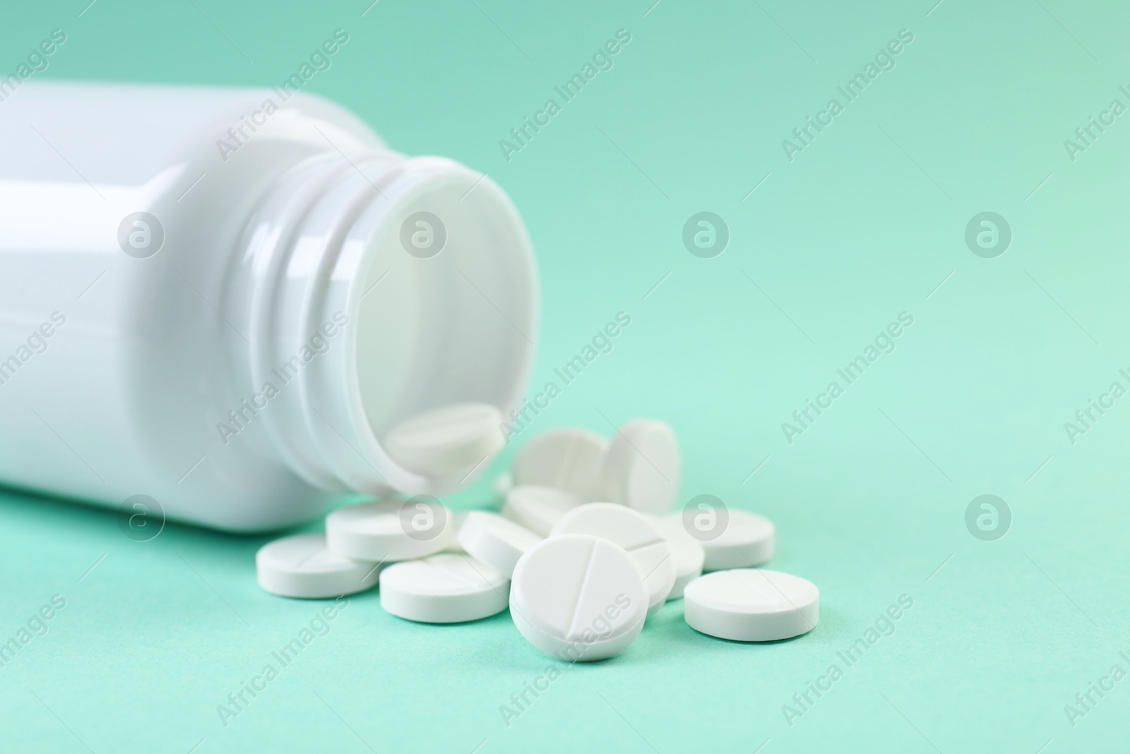 Photo of Bottle of antibiotic pills on turquoise background, closeup. Space for text