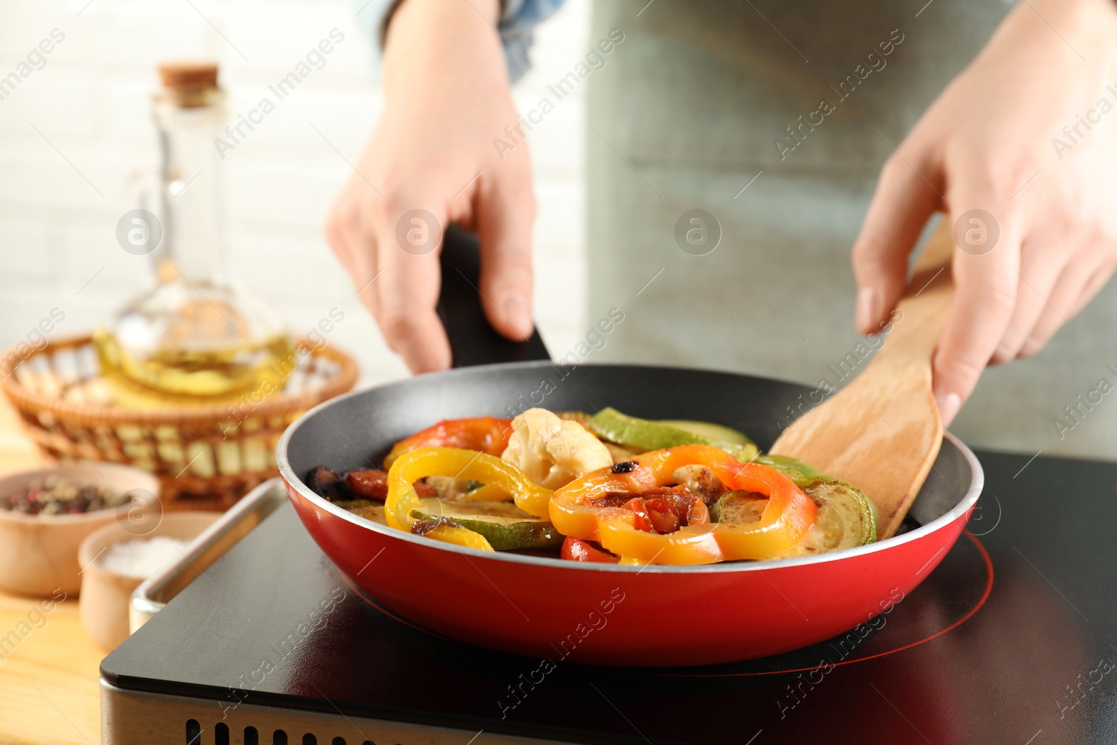 Photo of Woman frying vegetables in pan on stove at table indoors, closeup