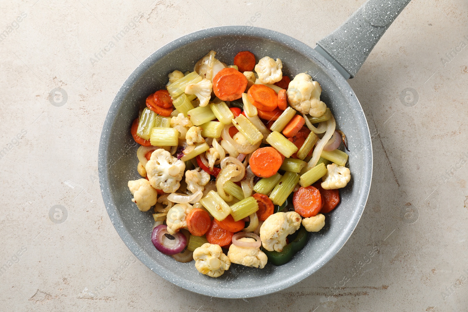 Photo of Frying pan with vegetables on light textured table, top view