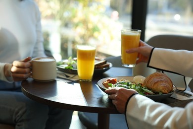 Photo of Women having tasty breakfast in cafe, closeup