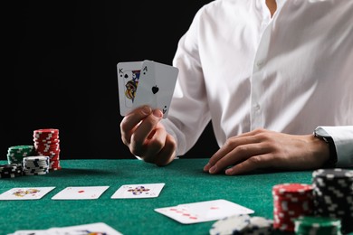 Photo of Man with cards and casino chips playing poker at gambling table, closeup