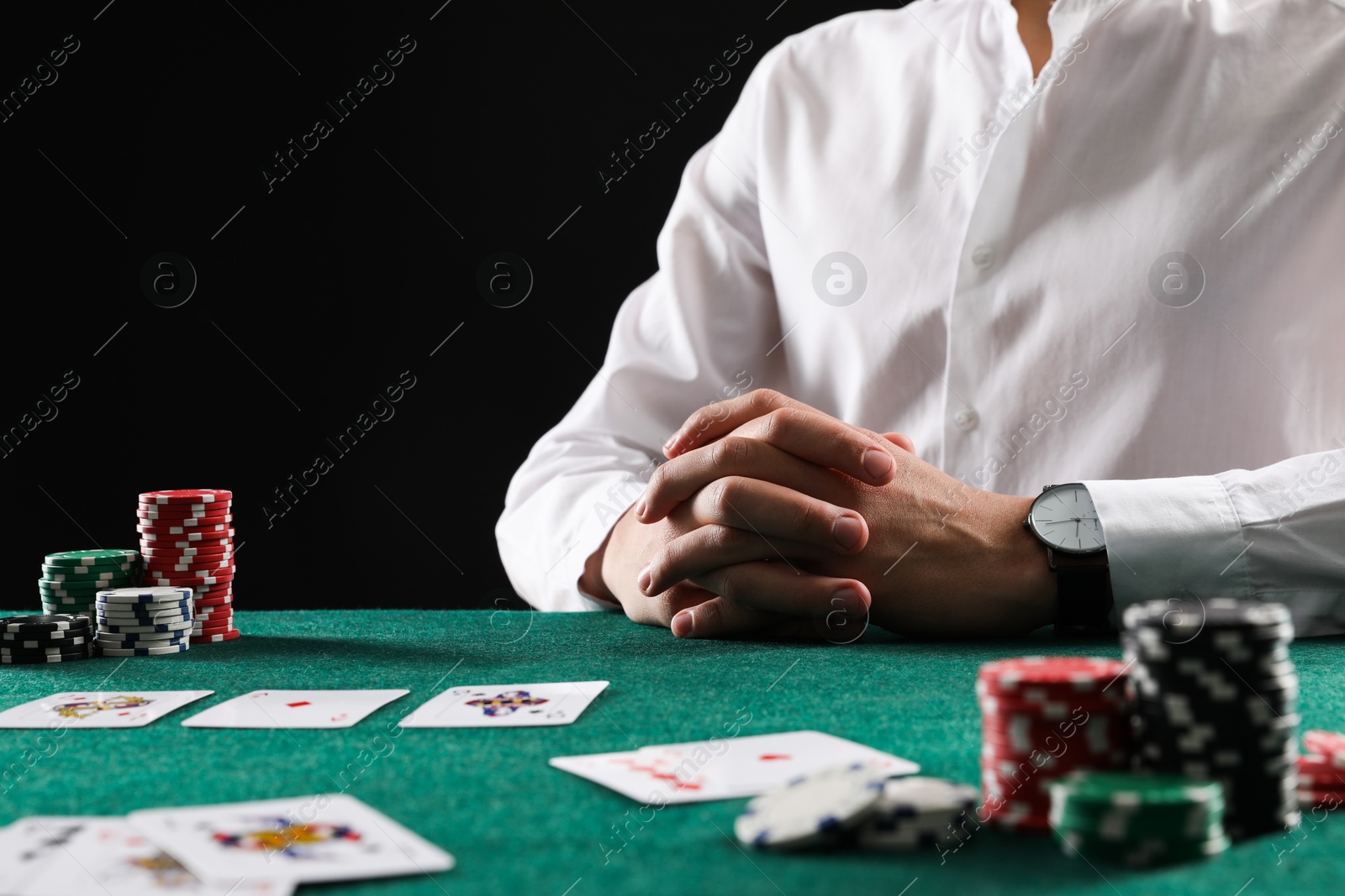 Photo of Man with cards and casino chips playing poker at gambling table, closeup