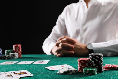 Photo of Man with cards and casino chips playing poker at gambling table, closeup