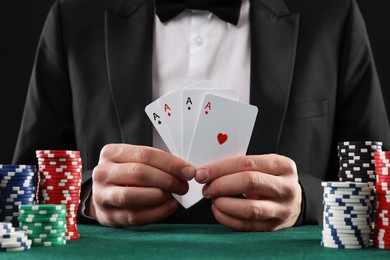 Photo of Man with cards and casino chips playing poker at gambling table, closeup