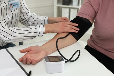 Photo of Nutritionist measuring overweight woman's blood pressure at desk in hospital, closeup