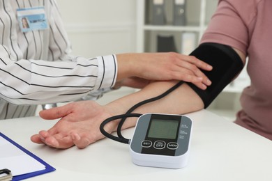 Photo of Nutritionist measuring overweight woman's blood pressure at desk in hospital, closeup