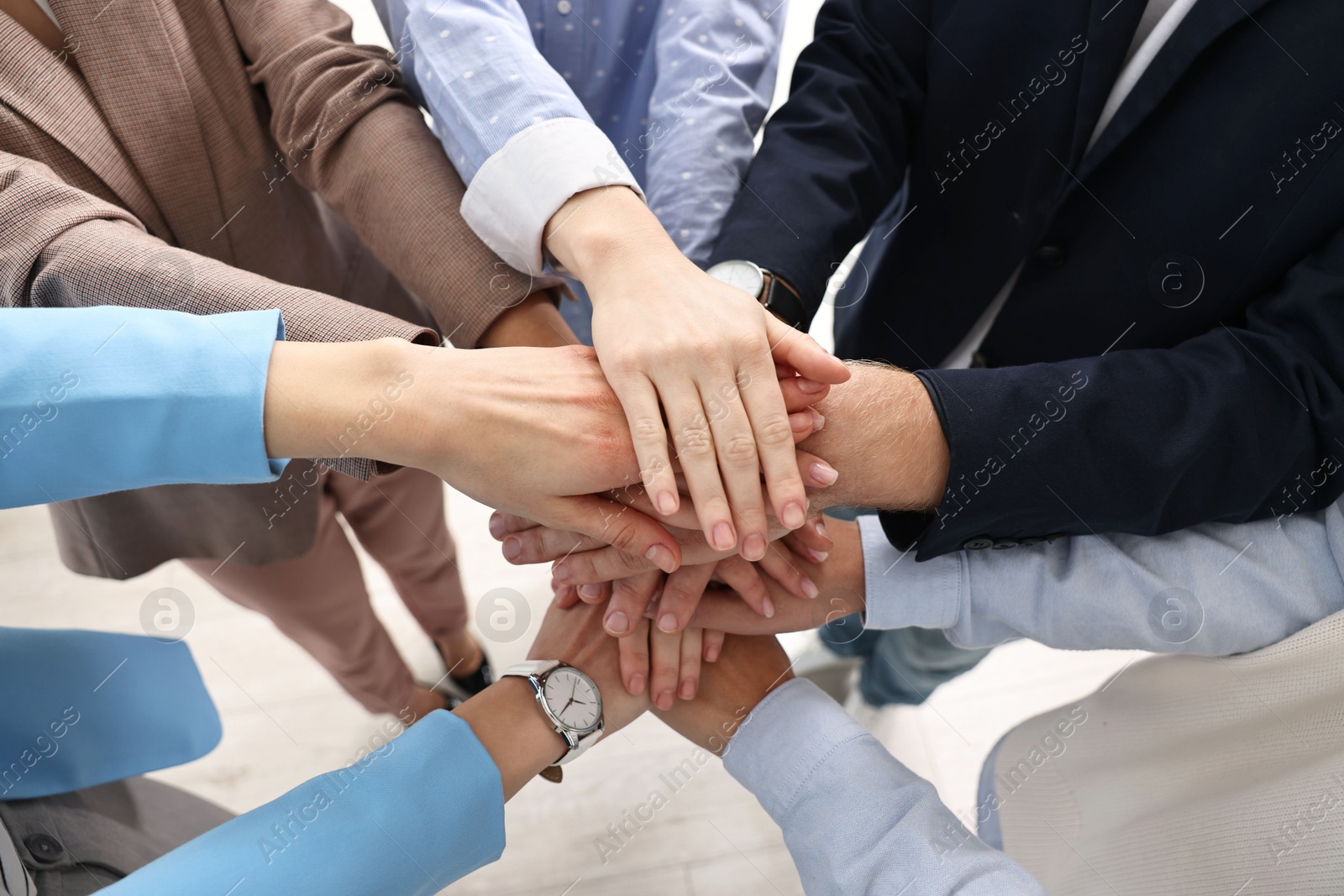 Photo of Teamwork. Group of people joining hands together indoors, above view