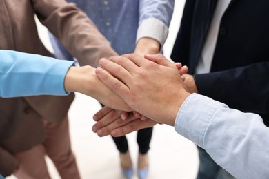 Photo of Teamwork. Group of people joining hands together indoors, closeup