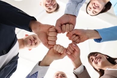 Photo of Teamwork. Group of people joining fists together indoors, bottom view