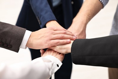 Teamwork. Group of people joining hands together indoors, closeup