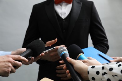 Photo of Group of journalists interviewing businessman on grey background, closeup