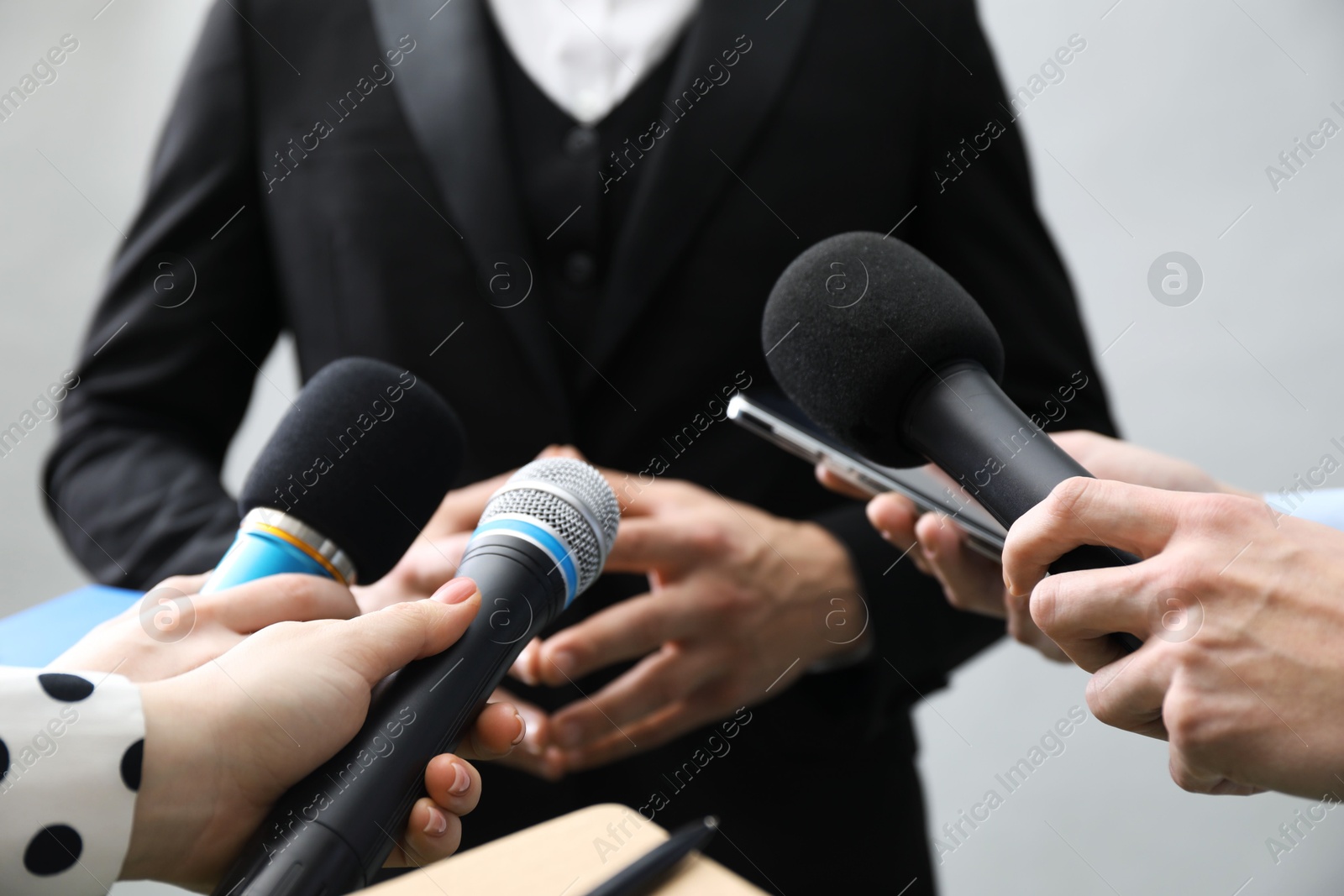 Photo of Group of journalists interviewing businessman on grey background, closeup