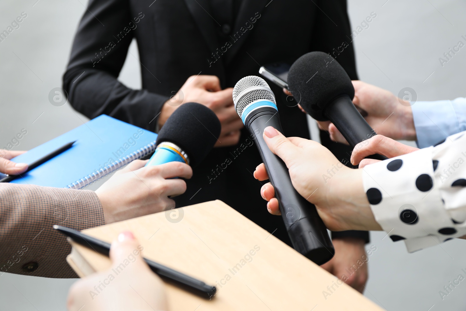 Photo of Group of journalists interviewing businessman on grey background, closeup