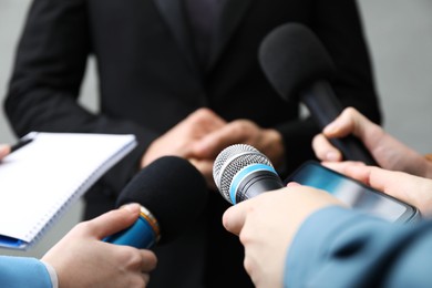 Photo of Group of journalists interviewing businesswoman on grey background, closeup