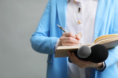 Photo of Journalist with microphones taking notes on grey background, closeup. Space for text