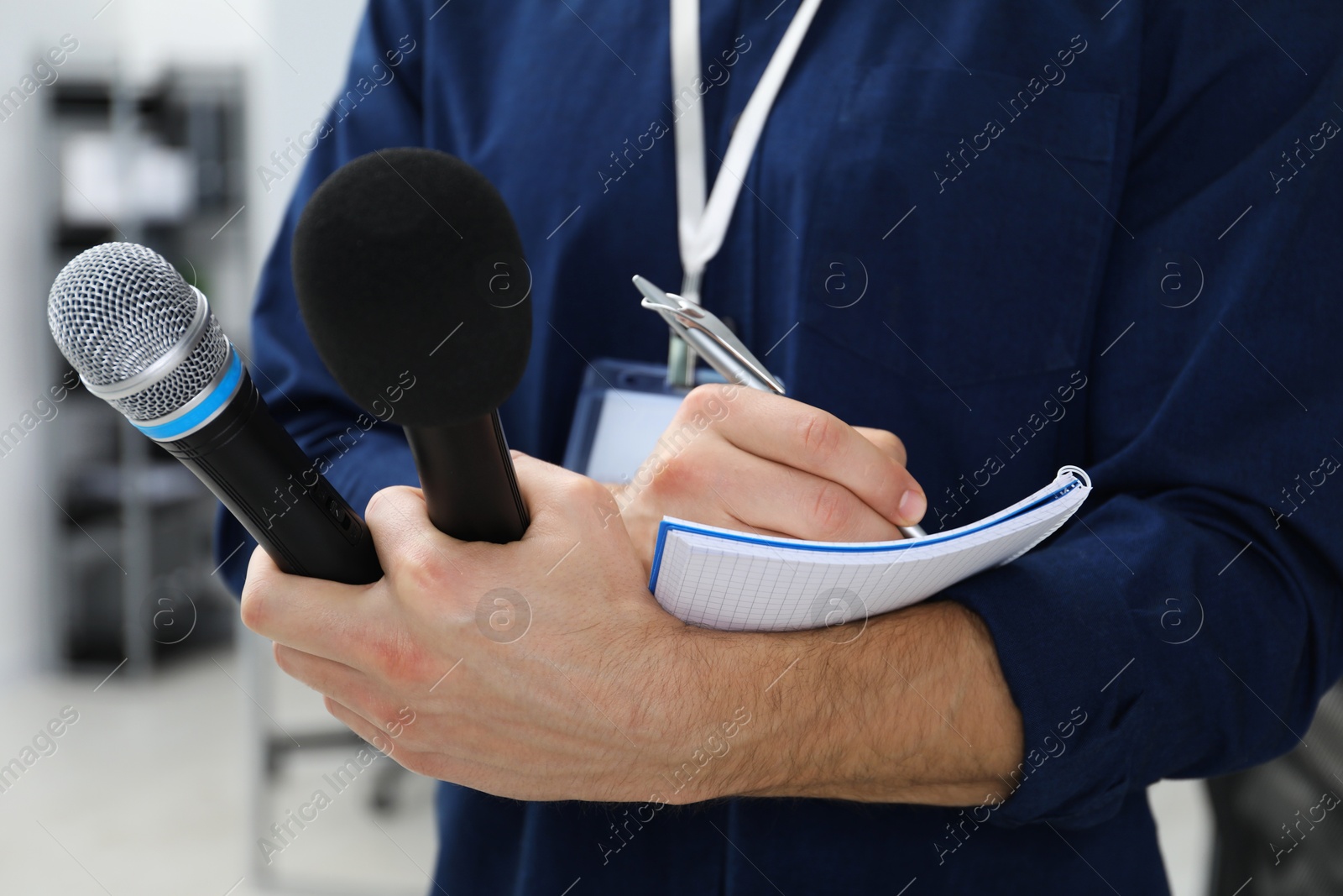 Photo of Journalist with microphones taking notes indoors, closeup