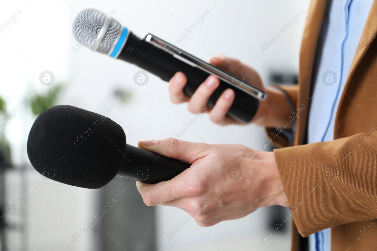 Photo of Journalist with microphones and smartphone indoors, closeup