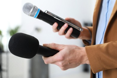 Photo of Journalist with microphones and smartphone indoors, closeup