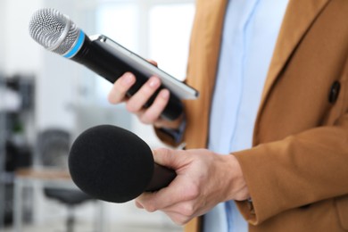 Photo of Journalist with microphones and smartphone indoors, closeup