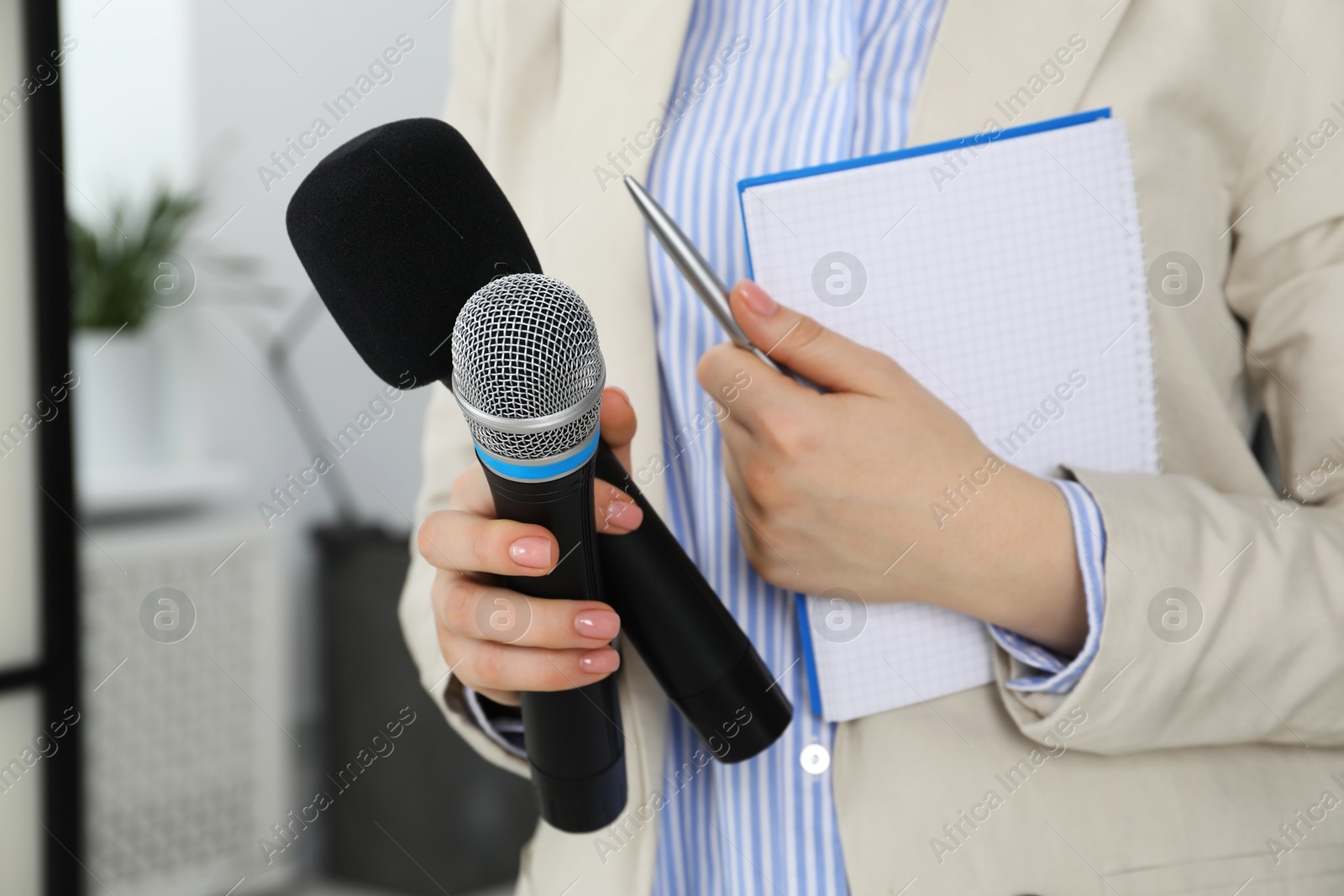 Photo of Journalist with microphones, notebook and pen indoors, closeup