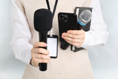 Photo of Journalist with microphones, smartphone and notebook on grey background, closeup