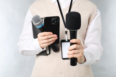 Photo of Journalist with microphones, smartphone and notebook on grey background, closeup