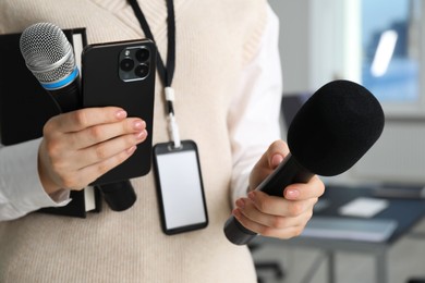 Photo of Journalist with microphones, smartphone and notebook indoors, closeup