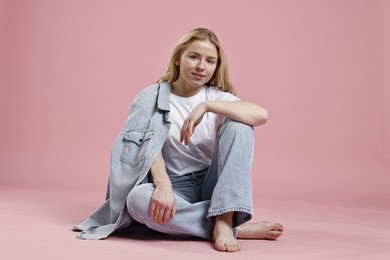 Photo of Smiling woman in stylish jeans on pink background