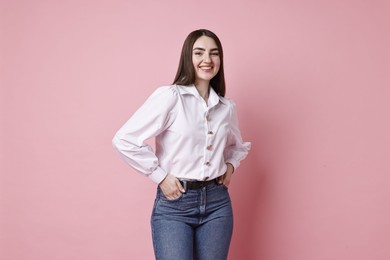 Photo of Smiling woman in stylish jeans on pink background