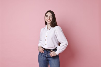 Photo of Smiling woman in stylish jeans on pink background