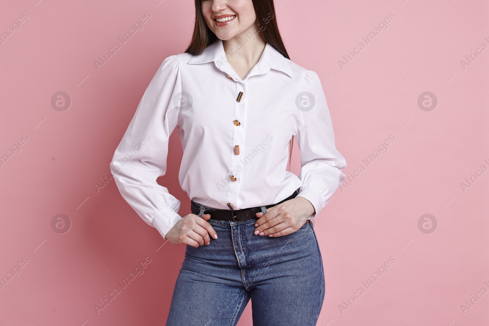 Photo of Smiling woman in stylish jeans on pink background, closeup