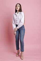 Photo of Beautiful young woman in stylish jeans on pink background