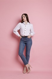 Photo of Beautiful young woman in stylish jeans on pink background