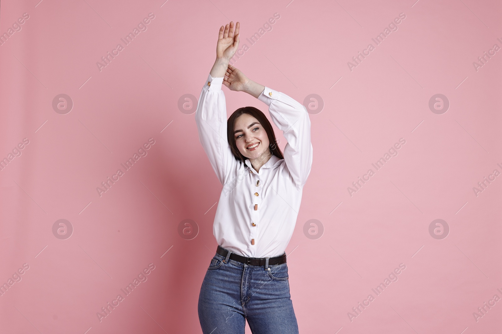 Photo of Smiling woman in stylish jeans on pink background