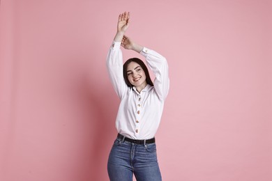 Photo of Smiling woman in stylish jeans on pink background