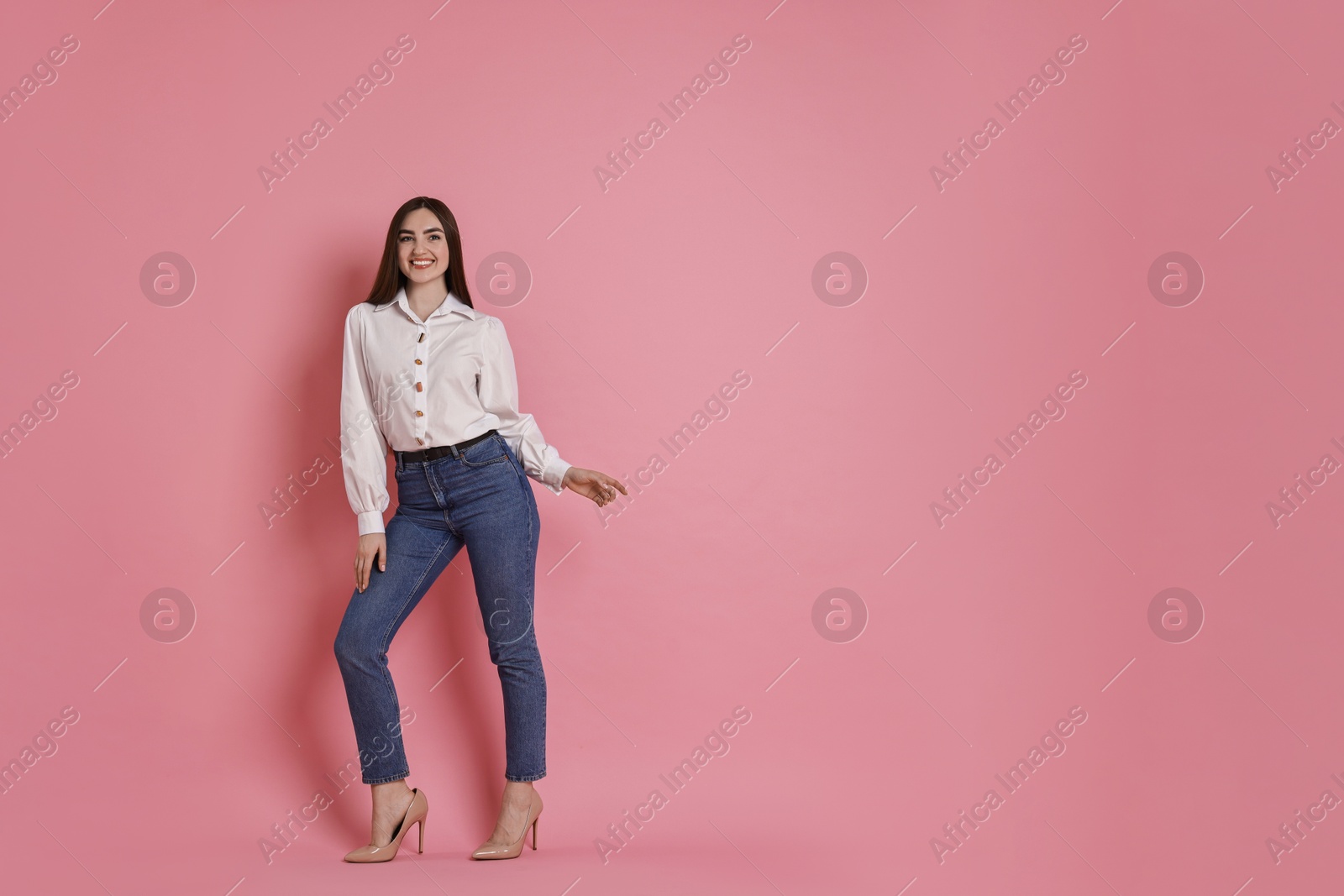 Photo of Happy woman in stylish jeans on pink background. Space for text