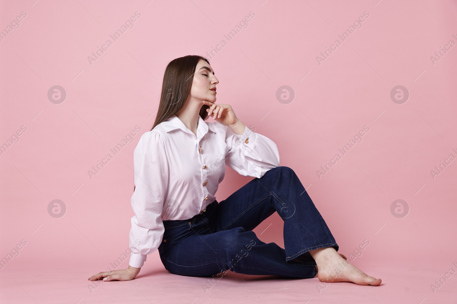 Photo of Beautiful young woman in stylish jeans on pink background