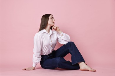 Photo of Beautiful young woman in stylish jeans on pink background